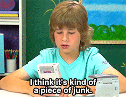 A kid at a school desk with a handheld console, captioned: I think it is kind of a piece of junk.