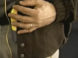 A hand tucking yellow headphone cables into a jacket.